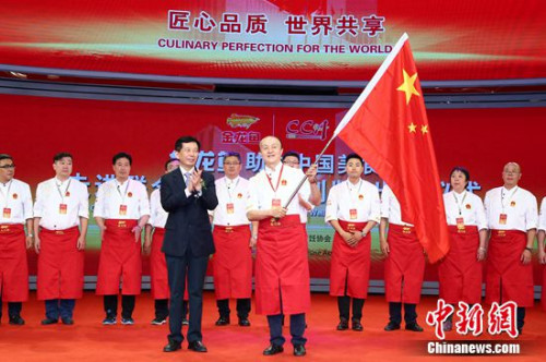 中国烹饪协会会长姜俊贤向即将出征纽约联合国总部的中国名厨代表团授予旗帜